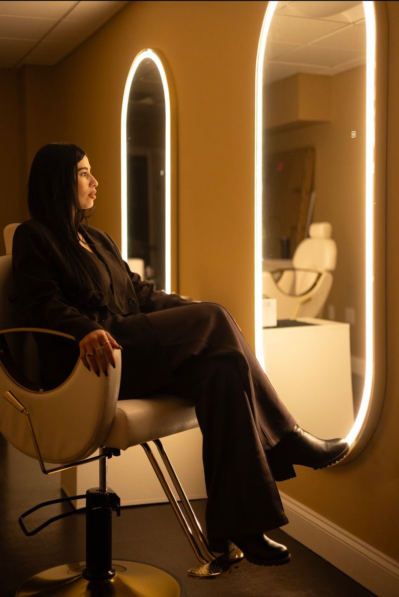 BellaFace client seated in a styling chair between lit arched mirrors in the spa